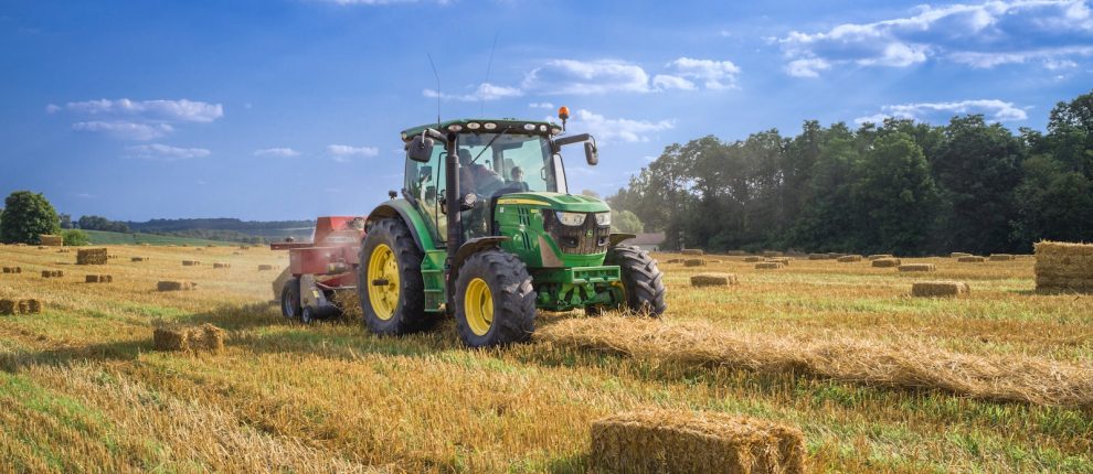 green tractor on brown grass field under blue sky during daytime
